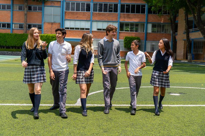 Estudiantes caminan juntos en el campo de deportes de la escuela durante el recreo.